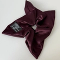 Close-up of deep wine red satin scrunchie with soft silk texture and handmade black woven label - Dark Wine Red