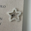 Macro detail of star-shaped crystal BB clip with intricate beaded texture on linen - Five-pointed Star / White Star