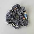 Close-up of gingham scrunchie featuring cute dog and cat embroidery patches - B Style Scrunchie