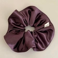 Detail view of smooth satin plum hair scrunchie with a white Hand Made woven label - Grape Purple
