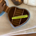 Macro view of blue denim heart jewelry box with green acetate hair clip on fabric - Green