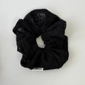 Detailopname van zwarte kanten scrunchie met bloemtextuur en merklabel aan de zijde - Zwart