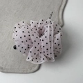 Close-up of elegant pleated mesh hair clip with black polka dots on beige fabric - Pink