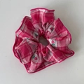 Detail eines rosa karierten Stoff-Haargummis mit Erdbeerstickerei und feinen Nähten - Rosa