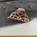 Detail of caramel brown weave hair claw clip on grey knitted fabric background - Brown