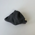 Close-up of grey striped fabric triangle storage pouch with lavender trim and gold emblem - Triangle