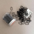 Elastic black hair ties set in a transparent jar with silver lid on textured background - Black