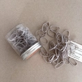 Detailed macro view of gray elastic hair ties set in a clear jar with a silver metal lid - Gray