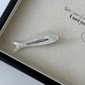 Detail of fish-shaped acetate hair clip with pearlescent white resin and metal duckbill grip - Off-white