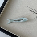 Macro view of mint green fish-shaped acetate hair clip with marble texture and rhinestone - Blue