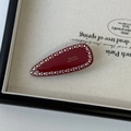 Macro shot of deep red barrette with colorful rhinestones and gold French lettering - Red