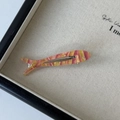 Close-up of a fish-shaped acetate hair clip with pink stripes and crystal eye detail - Orange
