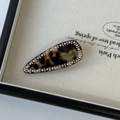 Macro detail of tortoiseshell acetate hair clip with sparkling rhinestones and gold engraving - Tortoiseshell