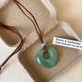 Macro shot of green natural stone heart pendant on brown cord with minimalist paper box - Aventurine Jade