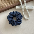 Dettaglio ravvicinato dell'elastico per capelli in denim blu scuro con cuciture bianche - Piccolo