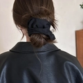 Detail of black fabric hair scrunchie with handmade label on a stylish bun hairstyle - Black