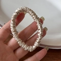 Close-up of champagne silk scrunchie showing detailed folds and smooth glossy texture - Beige