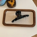 Detail of a black hair claw clip with colorful rhinestones on a wooden tray - Black