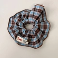 Detail van blauw-bruine geruite scrunchie met bruine knoop en Sweater Dog-label - Koffie Geruite Scrunchie