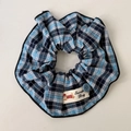 Detail van de blauwe ruitjes scrunchie met schattige hondenpatch en decoratieve knoop - Blauw Geruite Scrunchie