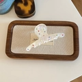 Detail of a pearlescent white hair claw clip with colorful rhinestones on a wooden tray - Mermaid Color