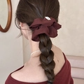 Deep red fabric scrunchie with Hand Made label on a braided hairstyle - Brown Red