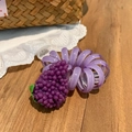Primer plano de coletero espiral morado con colgante de uva sobre mesa de madera - Uvas