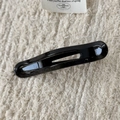 Détail d'une pince à cheveux en résine noire brillante avec un design ovale évidé épuré - Pince à bec de canard noire