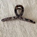 Detail view of a large leopard print hair claw clip on beige knitted fabric background - Gray Leopard Cross Style