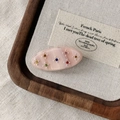 Detailed macro of oval acetate hair clip with colorful rhinestones on vintage canvas - Pink
