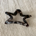 Detail view of star-shaped leopard print hair claw clip on soft knitted fabric background - Gray Leopard Star Style