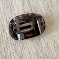 Detail of leopard print hair claw clip made of polished resin on a beige fabric background - Grey Tortoiseshell Hollow Duckbill Clip