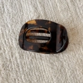 Detail view of tortoiseshell hair claw clip with amber pattern on knit background - Coffee Tortoiseshell Hollow Duckbill Clip