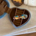 Dettaglio di un fermaglio per capelli ondulato in acetato in una scatola di jeans a cuore - Marmo Caffè Blu
