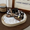 Close-up of a brown plaid bow hair claw clip with a luxury gold logo on a tray - Brown