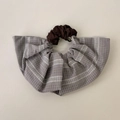 Dettaglio dell'elastico scrunchie a righe blu-grigio con ciondolo in metallo inciso - Elastico per capelli a balze a righe grigie