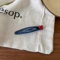 Détail de la pince à cheveux bleue avec cœur rouge 3D sur fond en toile beige - Style Coeur / Bleu Marine/Rouge
