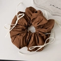 Detailaufnahme eines braunen Baumwoll-Scrunchies mit weißen Webseilen und Schleifendeko - Braun