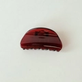 Dettaglio di un fermaglio per capelli rosso traslucido con finitura lucida su bianco - Semicerchio Stile