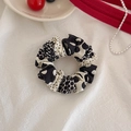 Close-up of a stylish black and white polka dot fabric scrunchie with pleated texture - Patchwork