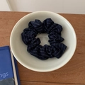 Detail of navy blue striped fabric scrunchie placed in a white ceramic bowl on a wooden desk - Navy Stripe