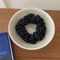 Detailopname van een zwart-witte polkadots stoffen scrunchie in een keramische kom - Grote Polkadot