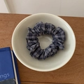 Detail van een blauw-grijs geruite stoffen scrunchie met plooien in een witte kom - Geruit Stijl