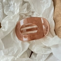 Detailed top view of a glossy caramel amber hair claw with marble texture on fabric - Brown