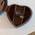 Dettaglio di un fermaglio tartarugato con strass colorati in una scatola a cuore blu - Tartarugato