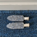 Detalle de dos pinzas metálicas para el pelo con cristaux grises sobre fondo azul - Azul