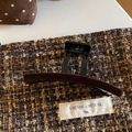 Macro detail of retro dark brown velvet claw clip on warm tweed fabric texture - Brown