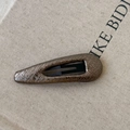 Vue macro d'une pince à cheveux géométrique avec motif de peau de serpent bronze - Style Goutte d'Eau Gris Champagne