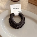 Detalle de coletero de seda en marrón café sobre un plato de cerámica decorativo - Serie Café Oscuro