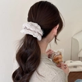 Cream knit hair scrunchie with hollow texture and decorative woven label on model - Beige